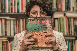 shallow focus photo of a woman holding van gogh book