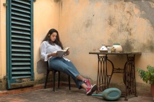 woman in white long sleeve shirt and blue denim jeans sitting on black wooden chair